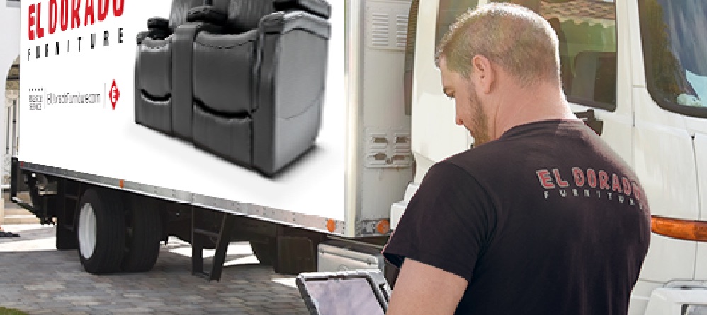 El Dorado Furniture driver checking his tablet beside a loaded delivery truck