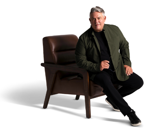 Anselmo Hernandez seated in a brown leather accent chair.