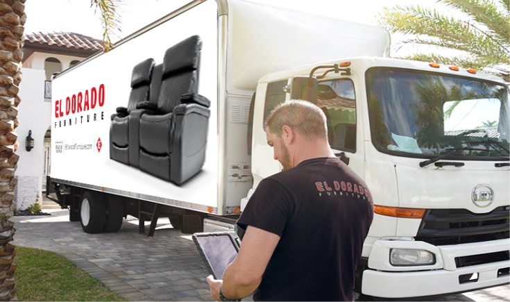 El Dorado Furniture delivery associate reviewing an order on a tablet beside a loaded delivery truck