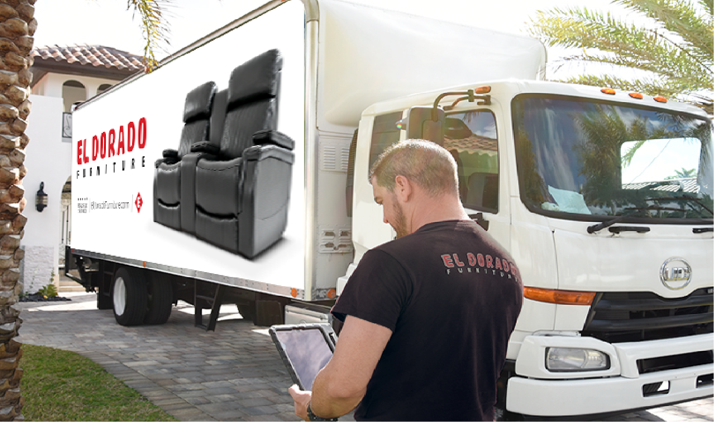 El Dorado Furniture delivery associate reviewing an order on a tablet in front of a delivery truck