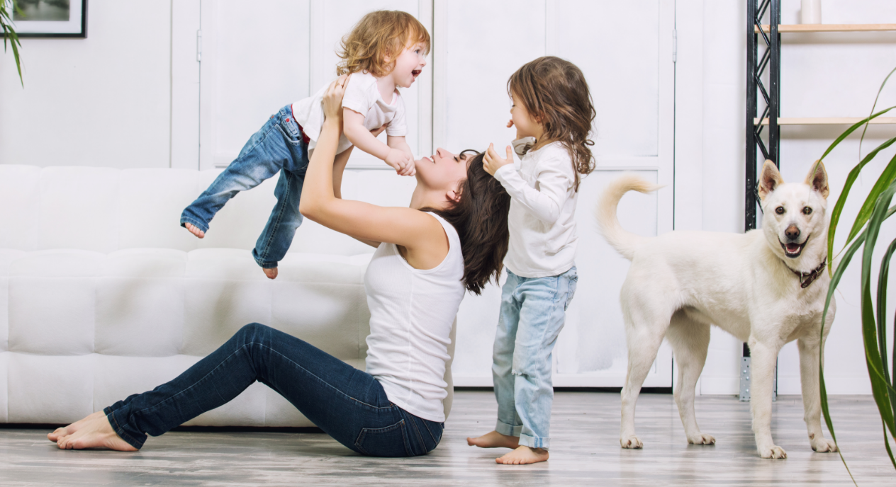 Family playing on the floor with their dog next to a sofa