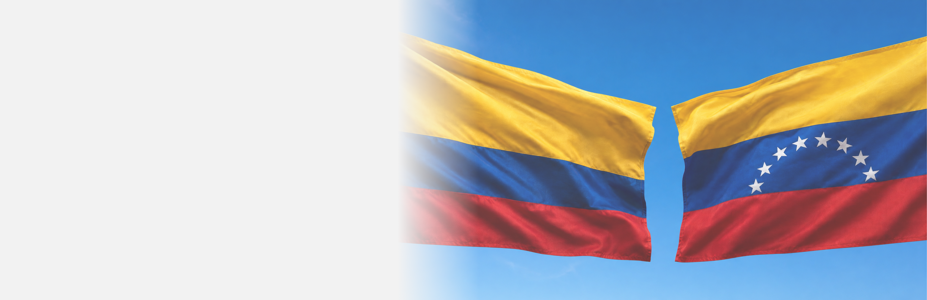 Colombian flag and a Venezuelan flag against blue skies flying in the air